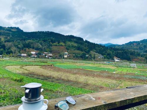 a cup on a fence with a view of a field at Moc's House bắc hà in Bắc Hà