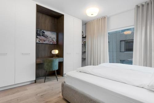 a white bedroom with a bed and a desk at Luxury Central Apartment in Reykjavík