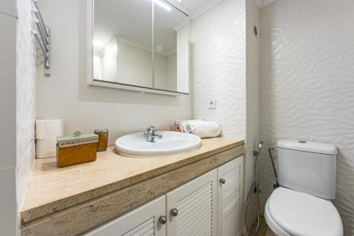a bathroom with a sink and a toilet and a mirror at 2 Bed-Sleeps 4-Vilamoura Beach-Pool-Spa-Balcony in Quarteira