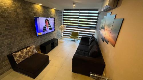 a living room with a couch and a tv on a brick wall at Navona Towers Amplio Apart, Dos Noches minimo, para 4 personas lo mejor de Panamá in Panama City