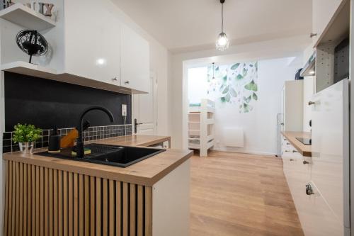 une cuisine avec des placards blancs et un mur noir dans l'établissement Rosamel - Studio à 1km de la gare proche port, à Étaples