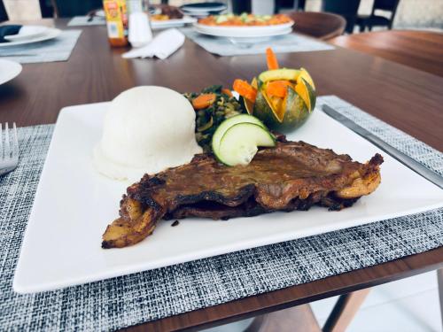 a plate of meat and vegetables on a table at Dikukama Executive Hotel in Tshabong