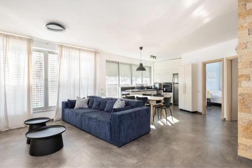 a living room with a blue couch and a kitchen at Best Location 3BR Specious Apartment By Vacay in Tel Aviv
