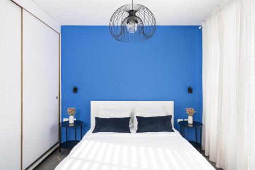 a blue bedroom with a white bed and blue walls at Best Location 3BR Specious Apartment By Vacay in Tel Aviv