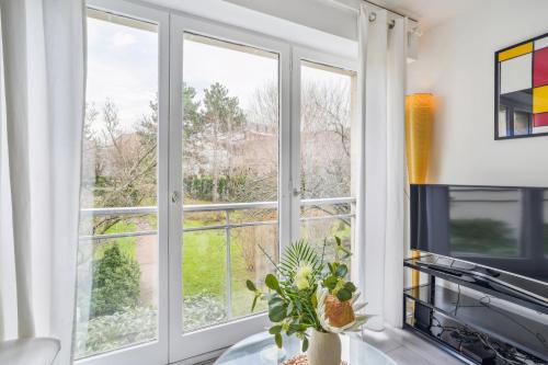 a kitchen with large windows and a table with a plant at Résidence AURMAT - Appart - Hôtel - Boulogne - Paris in Boulogne-Billancourt