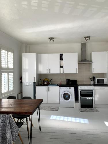 a kitchen with white appliances and a wooden table at Charming 2-Bedroom Maisonette in Leigh-on-Sea