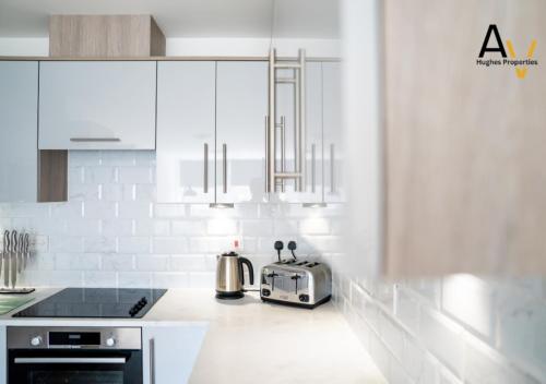 a kitchen with white cabinets and a toaster on the counter at Modern One-Bedroom Apartment - Central Location, Free Wi-Fi, 4 Mins from Station By AV Hughes Properties in Milton Keynes