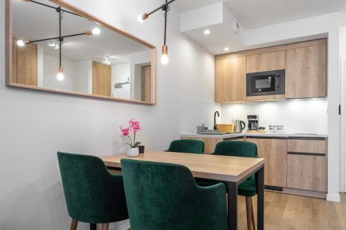 a kitchen and dining room with a wooden table and green chairs at RentPlanet - Apartamenty Zakopiańskie in Zakopane