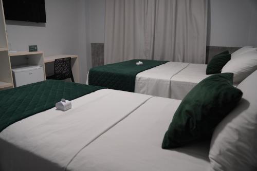 a hotel room with two beds with green and white sheets at Wai Hotel Picos in Picos