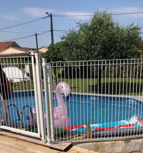 une clôture avec un jouet de porc rose devant une piscine dans l'établissement Maison proche d'Angoulême 8 couchages avec piscine, à Fléac