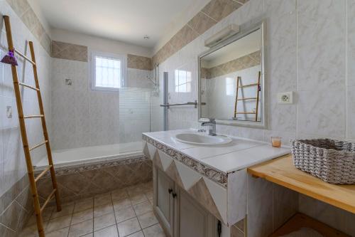 une salle de bain avec un lavabo, un miroir et une baignoire dans l'établissement Prouvençau - Piscine privée, à Aubignan