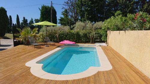 - une piscine sur une terrasse en bois avec un parasol dans l'établissement Prouvençau - Piscine privée, à Aubignan