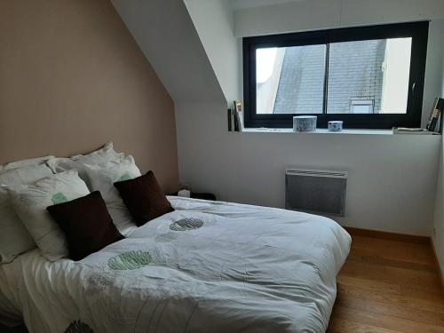 un lit dans une chambre avec une fenêtre dans l'établissement Ty Mélanie maison avec jardin, à Fouesnant