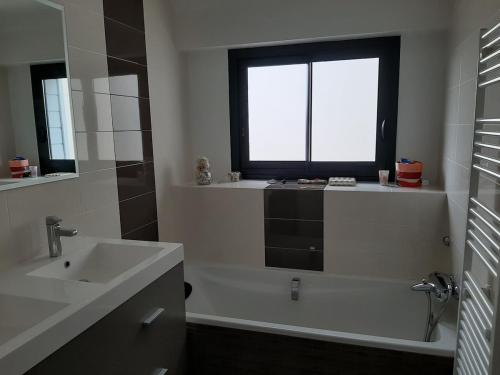 une salle de bain avec une baignoire, un lavabo et une fenêtre dans l'établissement Ty Mélanie maison avec jardin, à Fouesnant