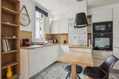 a kitchen with a table and a clock on the wall at Résidence AURMAT - Appart - Hôtel - Boulogne - Paris in Boulogne-Billancourt
