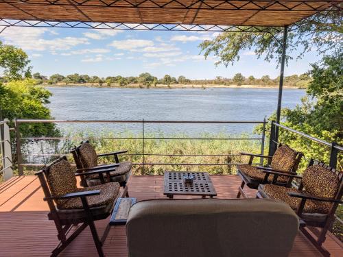 a deck with a table and chairs and a view of a river at Kayube Estate Bungalows in Livingstone