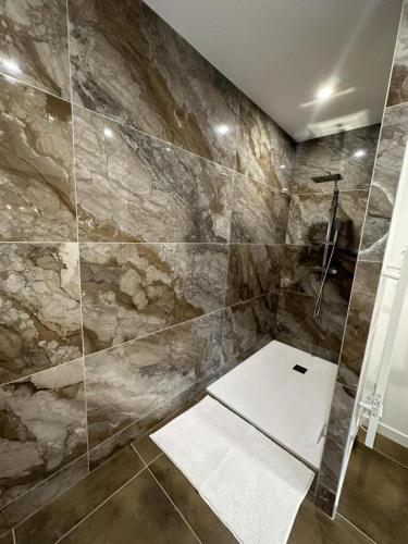 La salle de bains est pourvue d'une douche et d'un mur en pierre. dans l'établissement Gite de l'estampon, à Roquefort