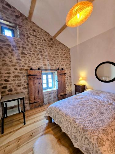 a bedroom with a bed and a stone wall at GITE LA MENOU in Usson-en-Forez