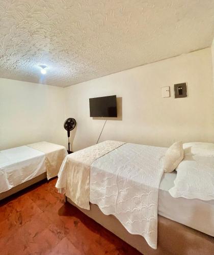 a bedroom with two beds and a flat screen tv at Hotel Casa Manta Cali in Cali