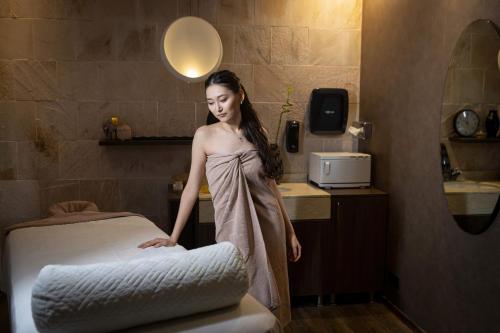 a woman standing next to a bed in a hotel room at Renaissance by Crystall in Atyraū