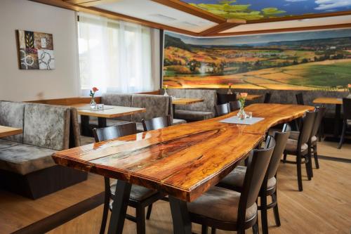a dining room with a large wooden table and chairs at Flair Hotel Landgasthof Roger in Löwenstein