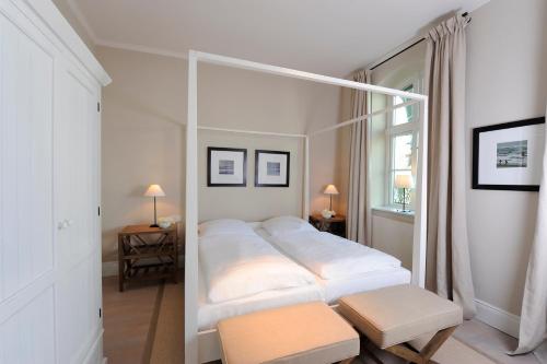 a bedroom with a white bed with a pole at Zollhaus 1 in Keitum