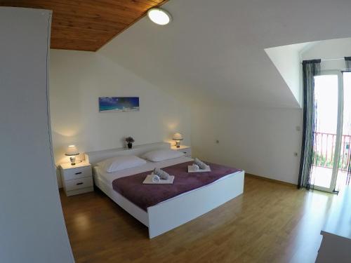 a white bedroom with a large bed with two lamps at Apartments Tomic in Dugi Rat