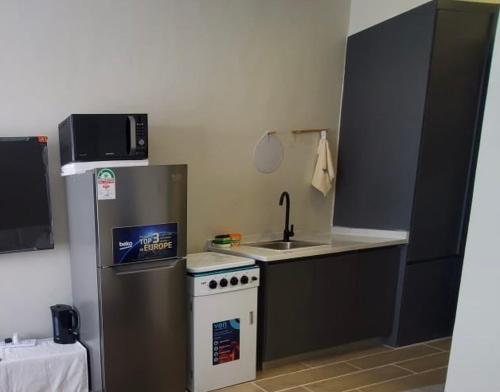 a kitchen with a refrigerator and a stove and a sink at Mimah's cozy getaway near JKIA at Taurus Residences in Nairobi