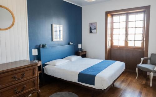 - une chambre bleue avec un lit et une chaise dans l'établissement Gîte du Lac, à Largillay-Marsonnay