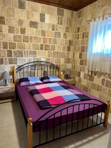 a bed in a bedroom with a brick wall at Stone House Retreat in Kalavárda