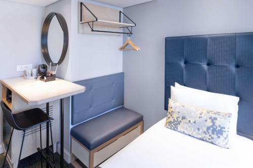 a bedroom with a blue headboard and a sink and a mirror at StayEasy Cape Town City Bowl in Cape Town