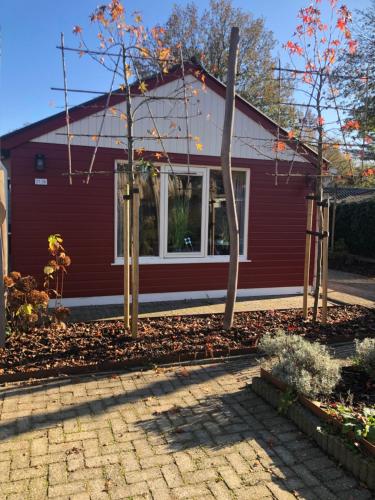 a red house with trees in front of it at Eekhoorn, vakantiehuis met barrelsauna in Voorthuizen
