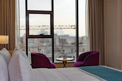 a hotel room with a bed and two chairs and a window at Grand Ambassador Hotel in Dubai