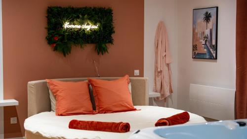 a bed with orange pillows and a sign on the wall at Comme chez soi - Amiens in Amiens