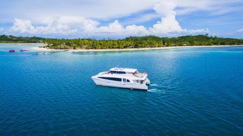 a white boat in the water with an island at Plantation Island Resort in Malolo Lailai