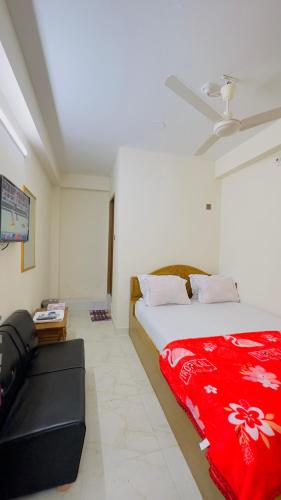 a bedroom with a bed with a red blanket and a couch at Hotel New Kalabgan Residential in Dhaka