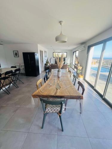 a dining room with a wooden table and chairs at "Villa Cavone" vue mer - piscine privée in Ventiseri