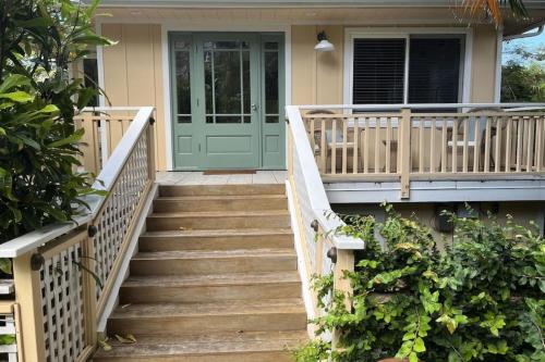 a front porch with a green door and stairs at The Yellow Cottage in Lanikai Your Perfect Island Getaway! in Kailua