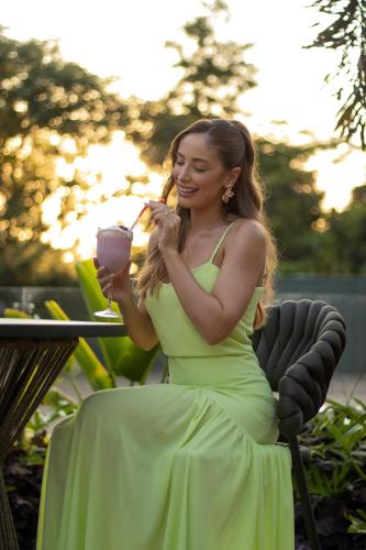 a woman in a green dress sitting in a chair with a drink at Cataratas Park Hotel e Eventos in Foz do Iguaçu