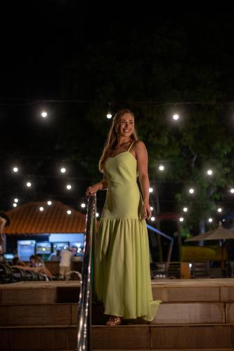 a woman in a green dress walking down stairs at Cataratas Park Hotel e Eventos in Foz do Iguaçu