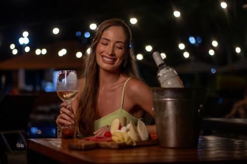 a woman sitting at a table with a glass of wine at Cataratas Park Hotel e Eventos in Foz do Iguaçu