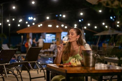 a woman sitting at a table drinking a glass of wine at Cataratas Park Hotel e Eventos in Foz do Iguaçu