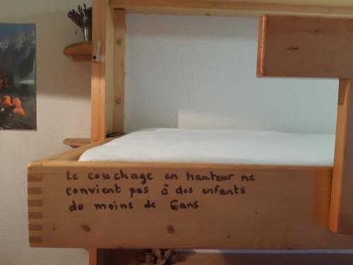 - un lit superposé en bois avec un panneau dans l'établissement Appartement Morillon 500m ski et randonnée, à Morillon