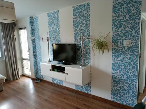 a living room with blue and white wallpaper and a tv at Centrum Pl Zwycięstwa dwu Pokojowe z balkonem in Piła
