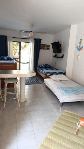 a room with two beds and a table and a tv at Edificio Mar de Leva in Santa Marta