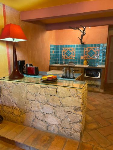 une cuisine avec un comptoir en pierre et une lampe. dans l'établissement Charmant duplex bucolique, piscine, en Provence, à Le Beaucet