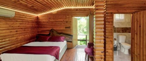a log cabin bedroom with two beds and a bathroom at Paradise Plus Ağva in Agva