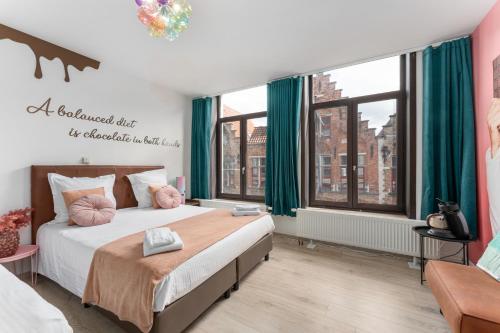 a bedroom with a large bed with green curtains at The Chocolate Suites in Bruges