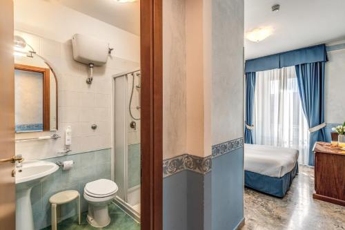 a bathroom with a toilet a sink and a bed at Hotel Orazia in Rome