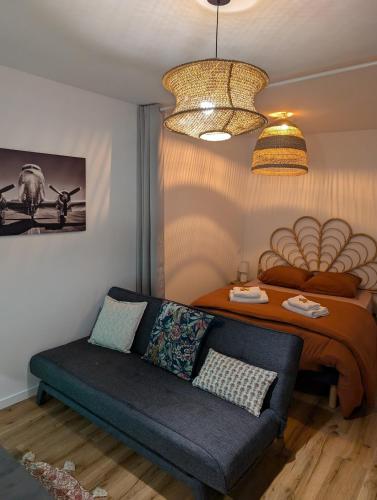 a living room with a couch and a bed at Charmant studio au coeur de la ville in Guer